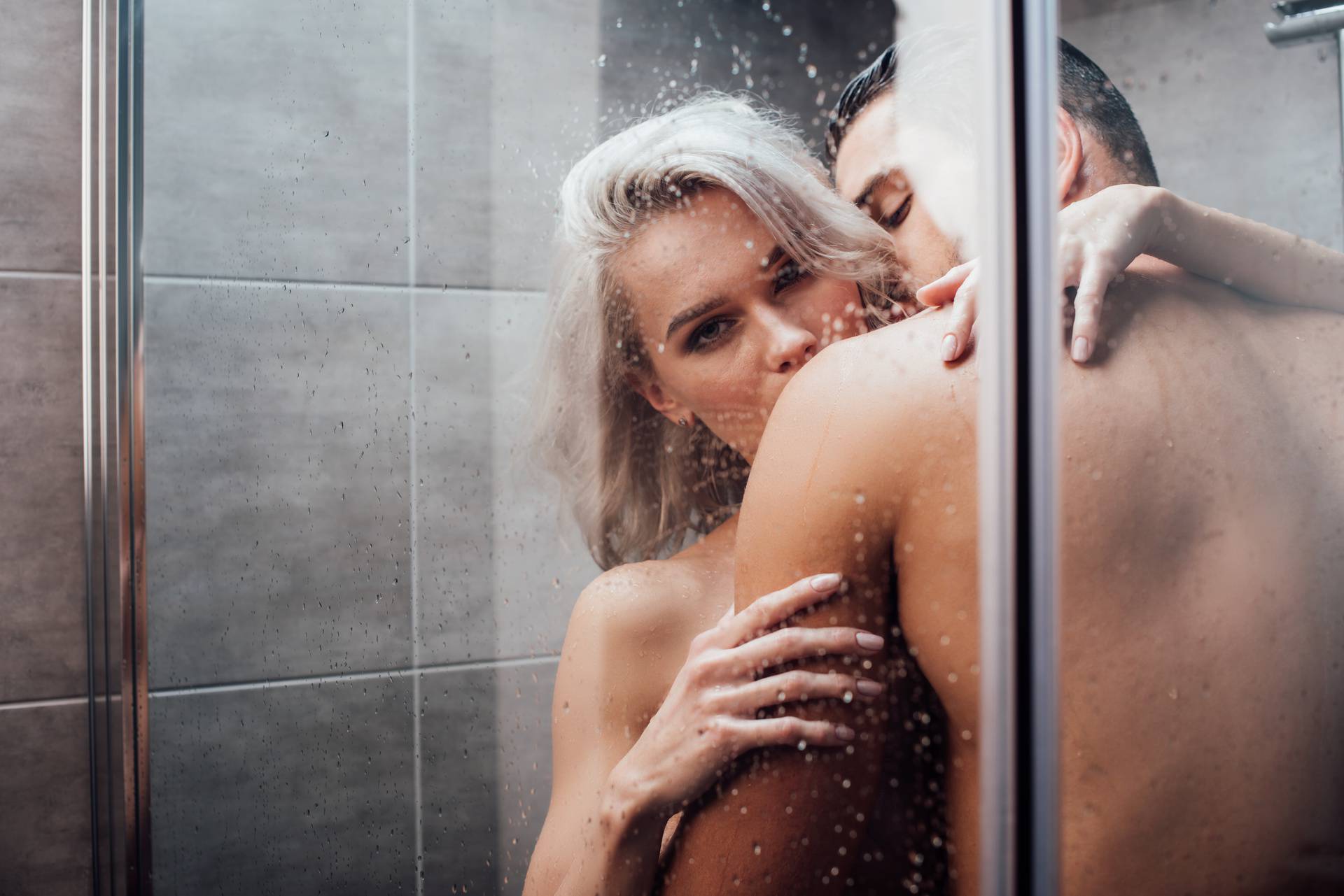 passionate man embracing and kissing beautiful woman in shower 