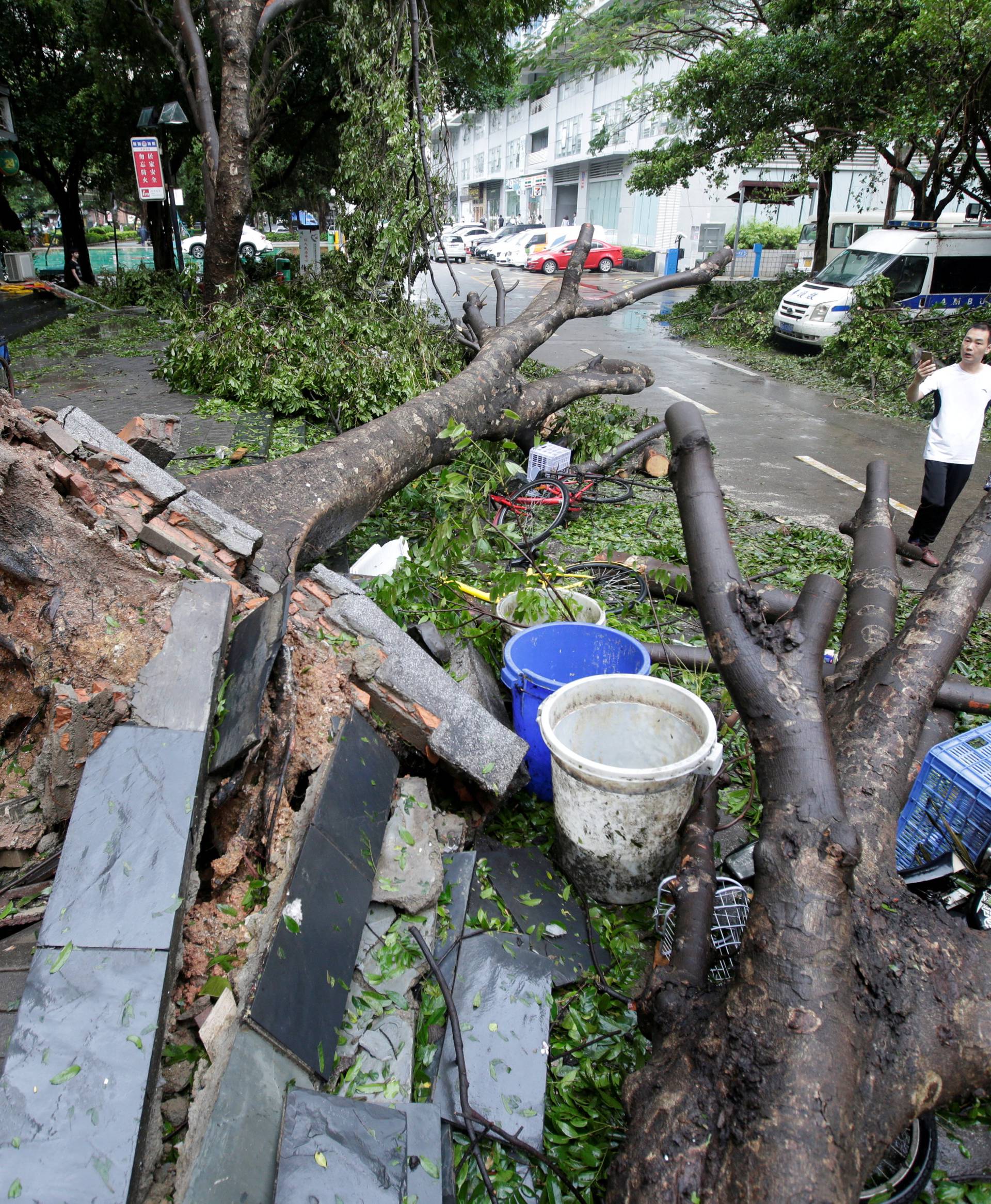 Man walks past uprooted trees on a damaged street after Typhoon Mangkhut hit Shenzhen