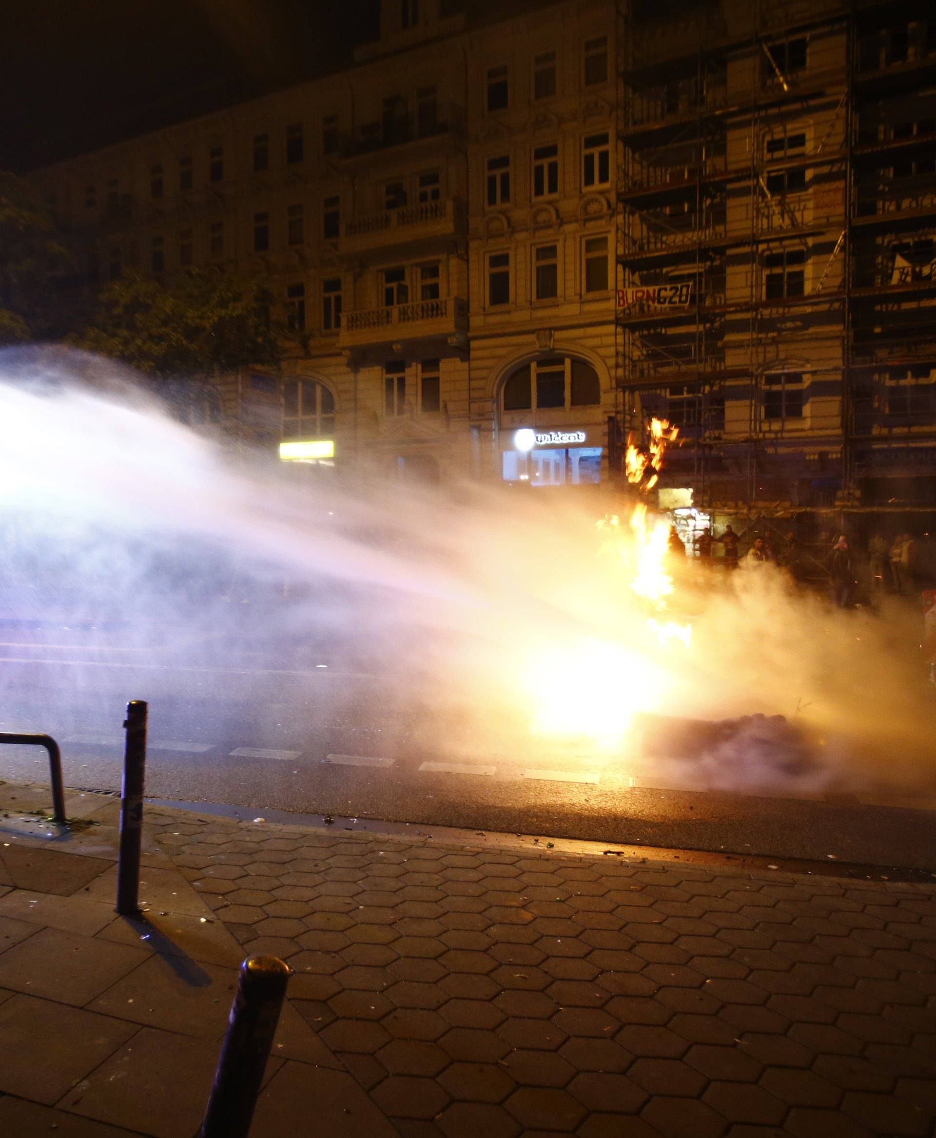 A man takes a picture as police use water cannon during the demonstration at the G20 summit in Hamburg
