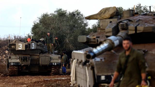 Israeli soldiers stand by their tanks near Israel's border with Lebanon in northern Israel