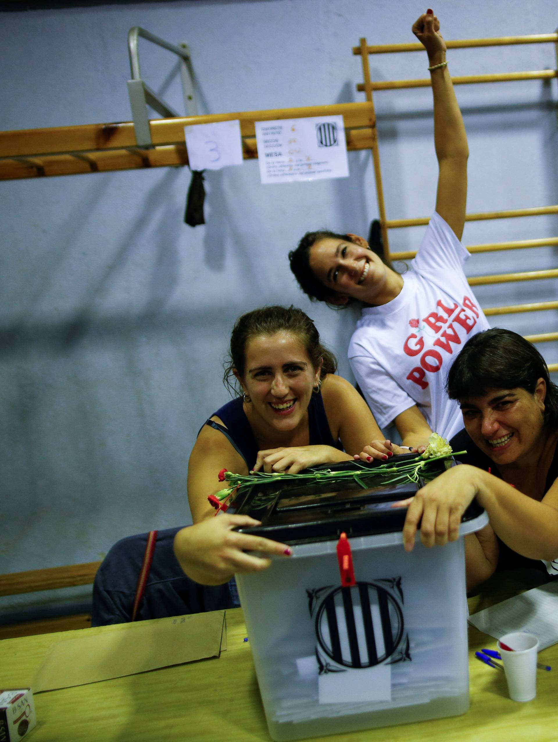 Poll workers celebrate after polls closed at a polling station for the banned independence referendum in Barcelona