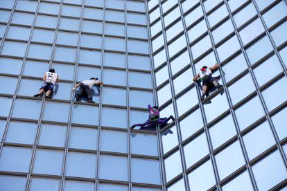 French Spiderman Alain Robert and climbers Martin Banot, Alexis Landot and Leo Urban climb a skyscraper in La Defense near Paris