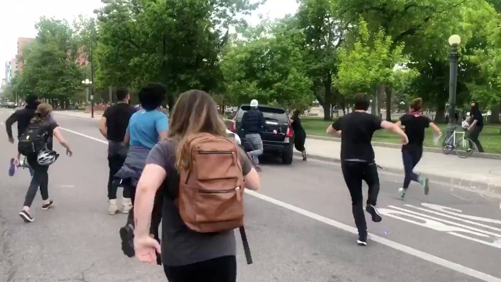 Protesters run after a vehicle speeding through a protest held in Denver held following the death of  George Floyd in Minneapolis