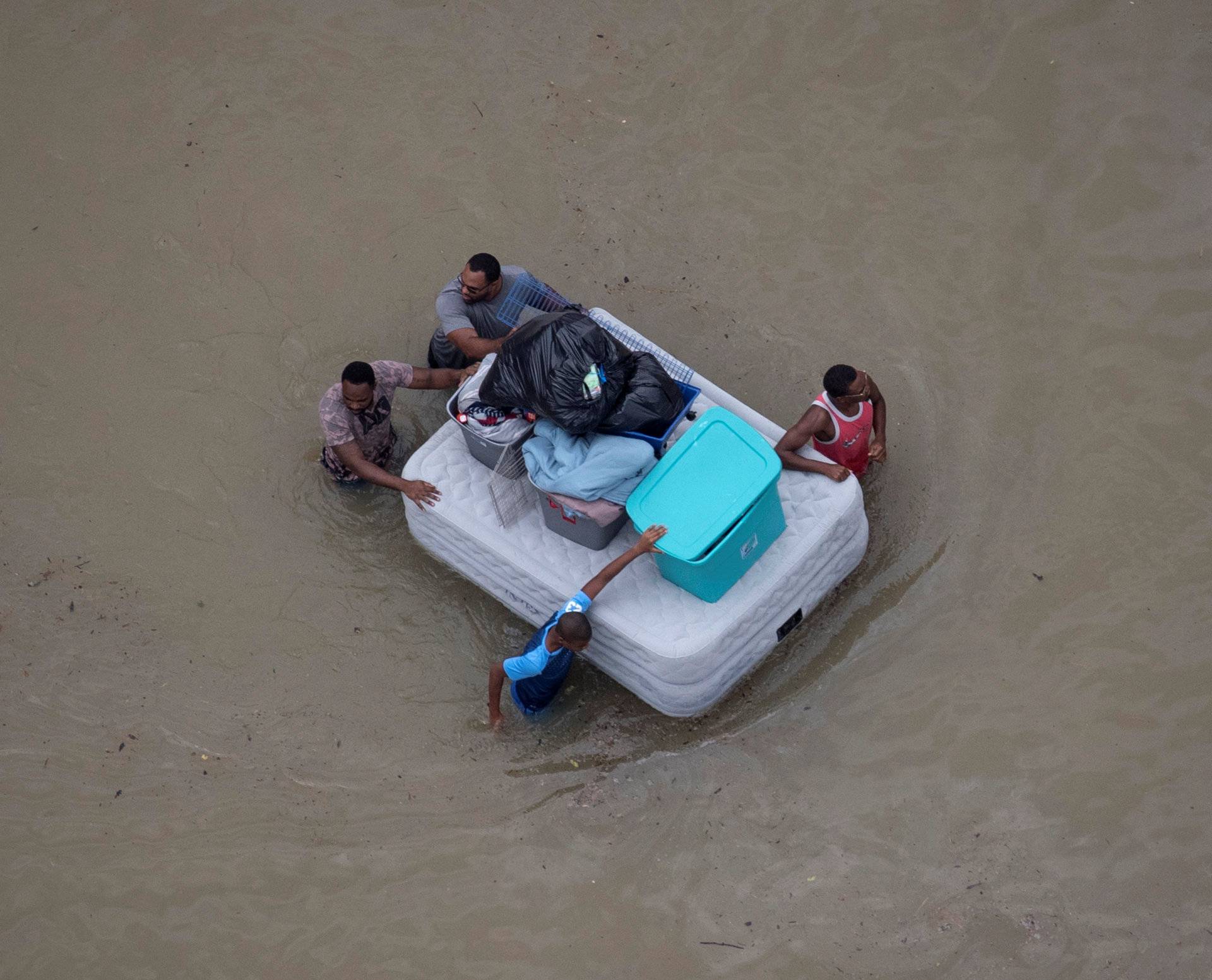 Residents wade with belongings through floods caused by Tropical Storm Harvey while awaiting rescue in Houston