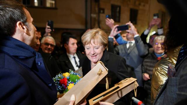 Outgoing German Chancellor Angela Merkel and France's President Emmanuel Macron receive flowers and a bottle of wine as gifts upon their arrival for talks, in Beaune