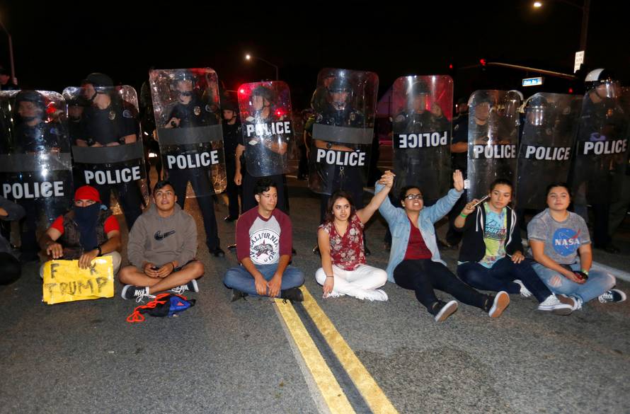 Demonstrators sit in front of a line of police in riot gear outside Republican U.S. presidential candidate Donald Trump's campaign rally in Costa Mesa, California 