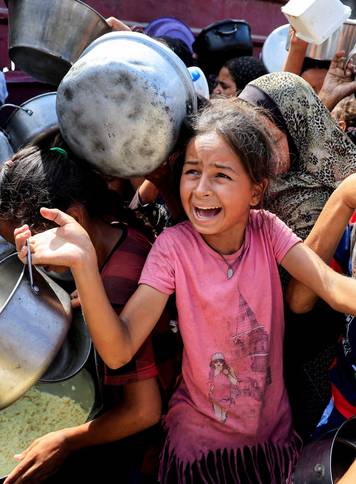 Palestinians wait to receive food from a charity kitchen, in Khan Younis