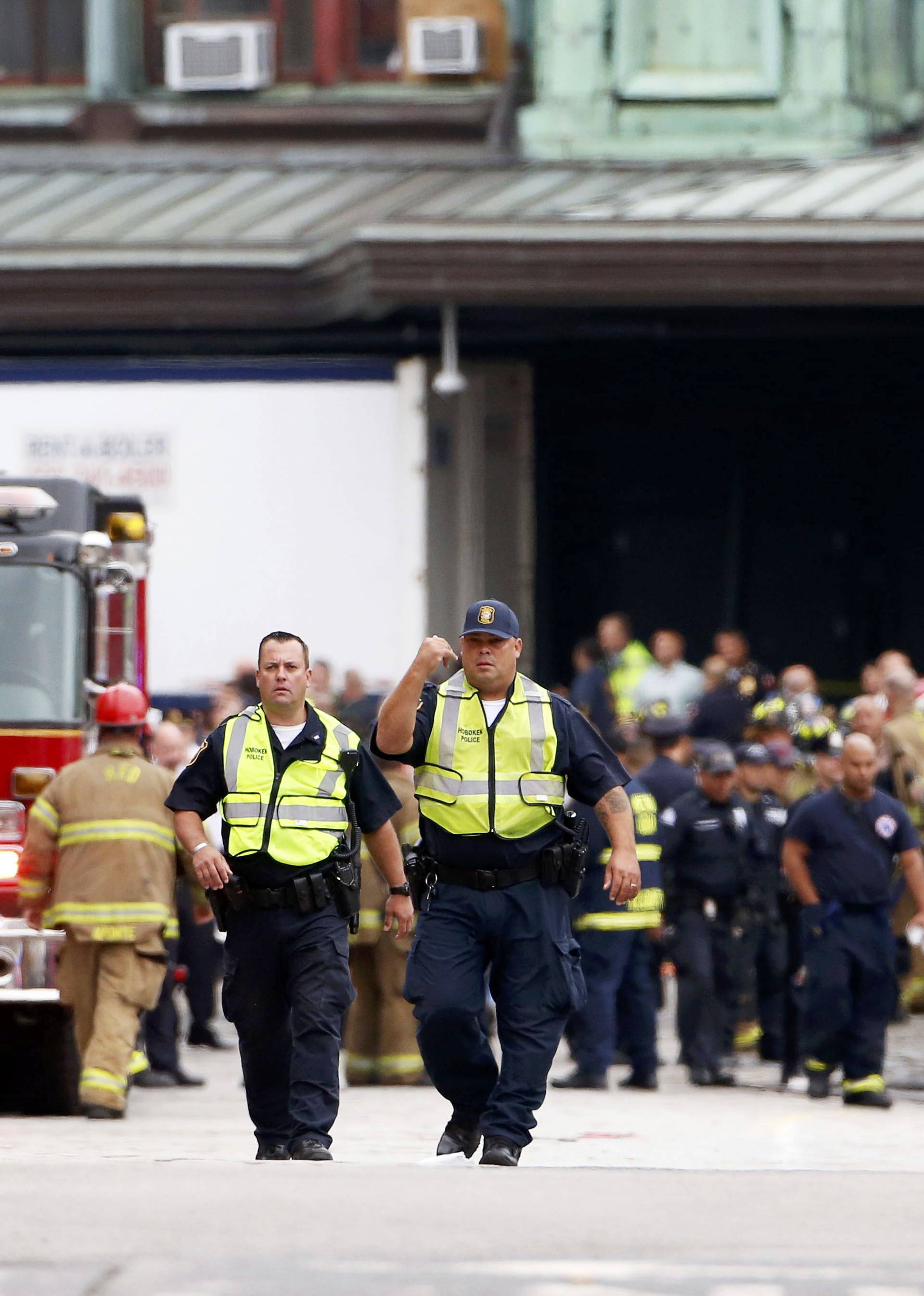 Hoboken police officers look over the scene of a train crash where a New Jersey Transit train derailed and crashed through the station, injuring more than 100 people, in Hoboken