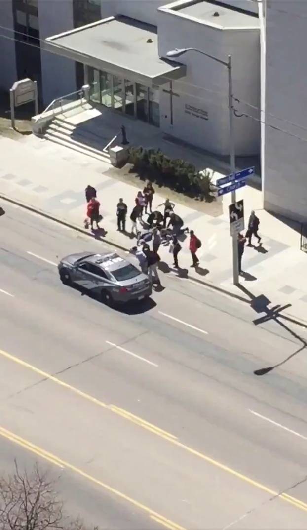 A victim is helped by pedestrians after a van hit multiple people at a major intersection in Toronto, Canada