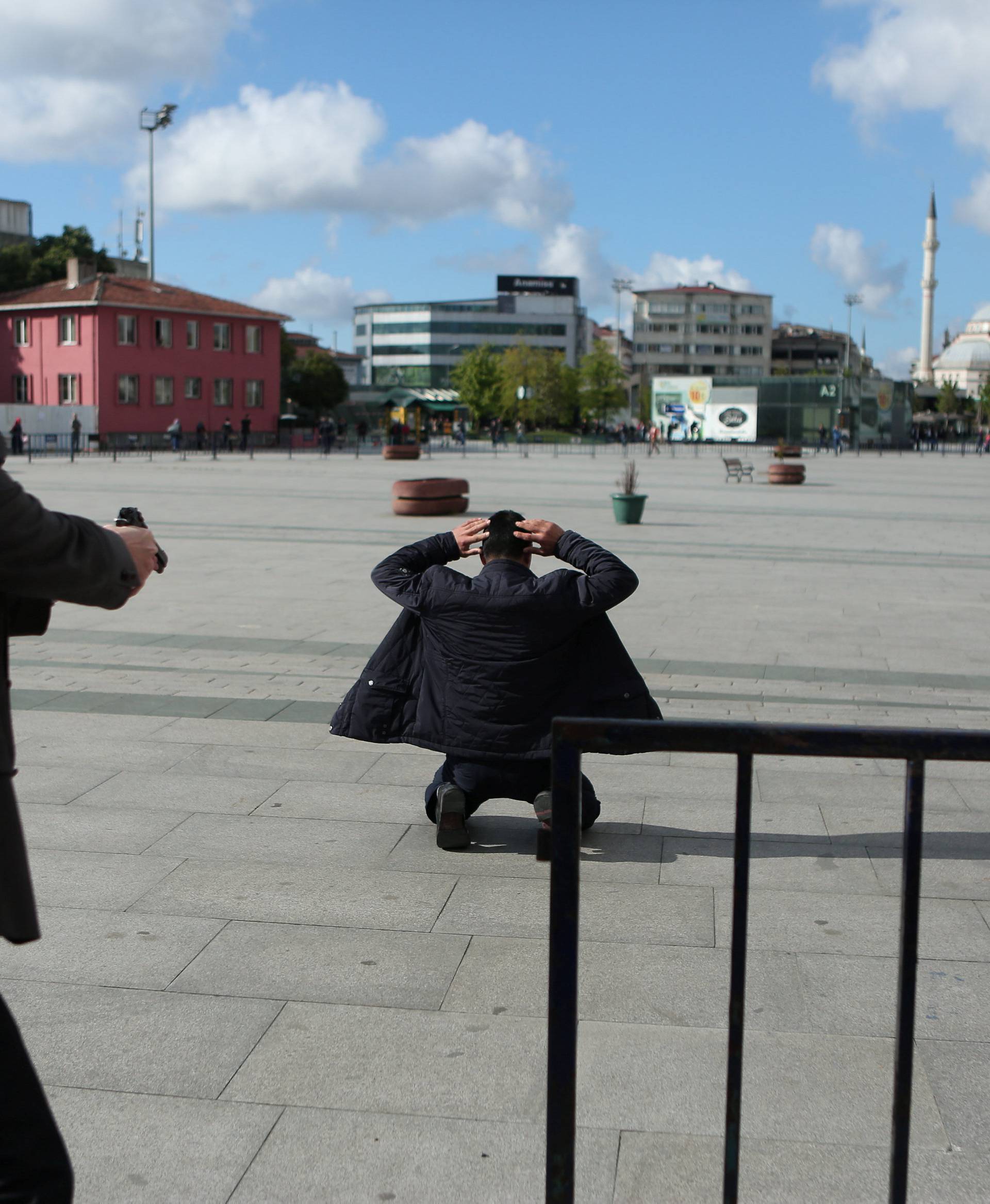 A plain clothes police officer points his gun at an assailant who attempted to shoot prominent Turkish journalist Can Dundar, outside a courthouse in Istanbul