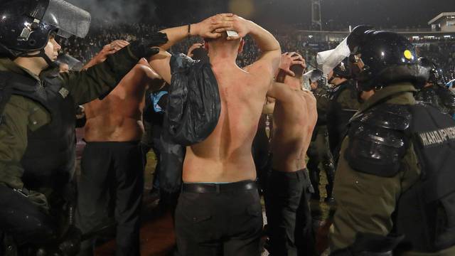 Police escort the soccer fans injured during the fights at a match between Red Star and Partizan in Belgrade