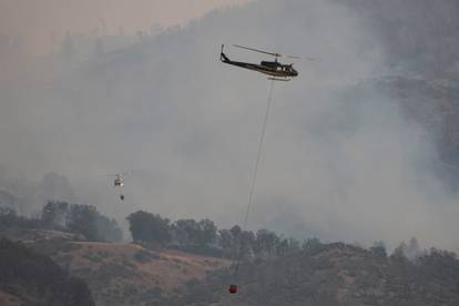 Helicopters and crew carry water to extinguish section of  LNU Lightning Complex Fire near Middletown, California