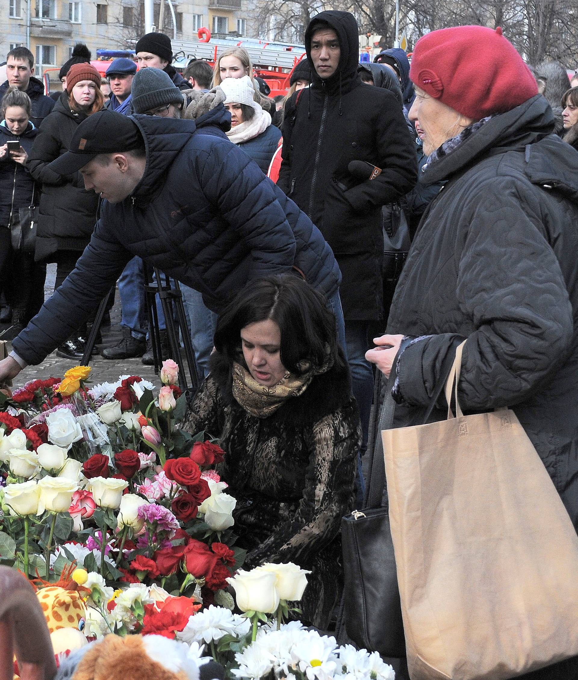People place toys and flowers at a makeshift memorial for the victims of a shopping mall fire in Kemerovo