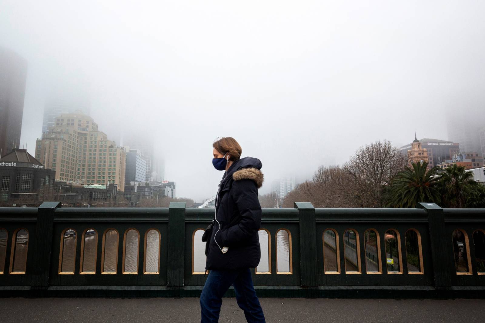 A person in a protective face mask walks along the Princes Bridge in Melbourne