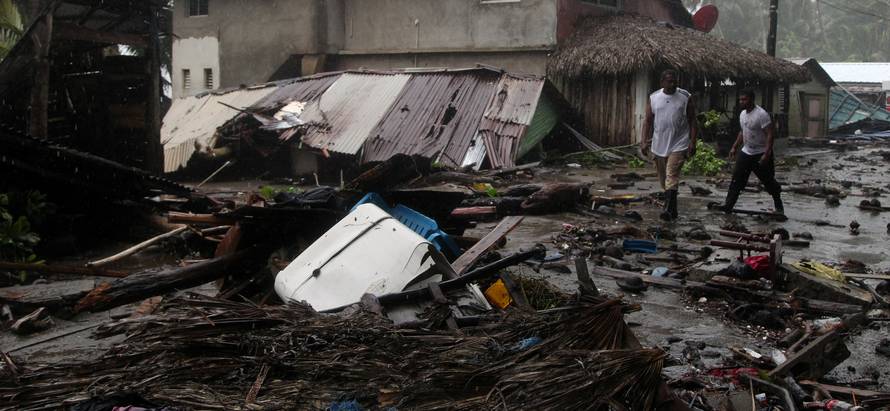 People walk past debris as Hurricane Irma moves off from the northern coast of the Dominican Republic, in Nagua