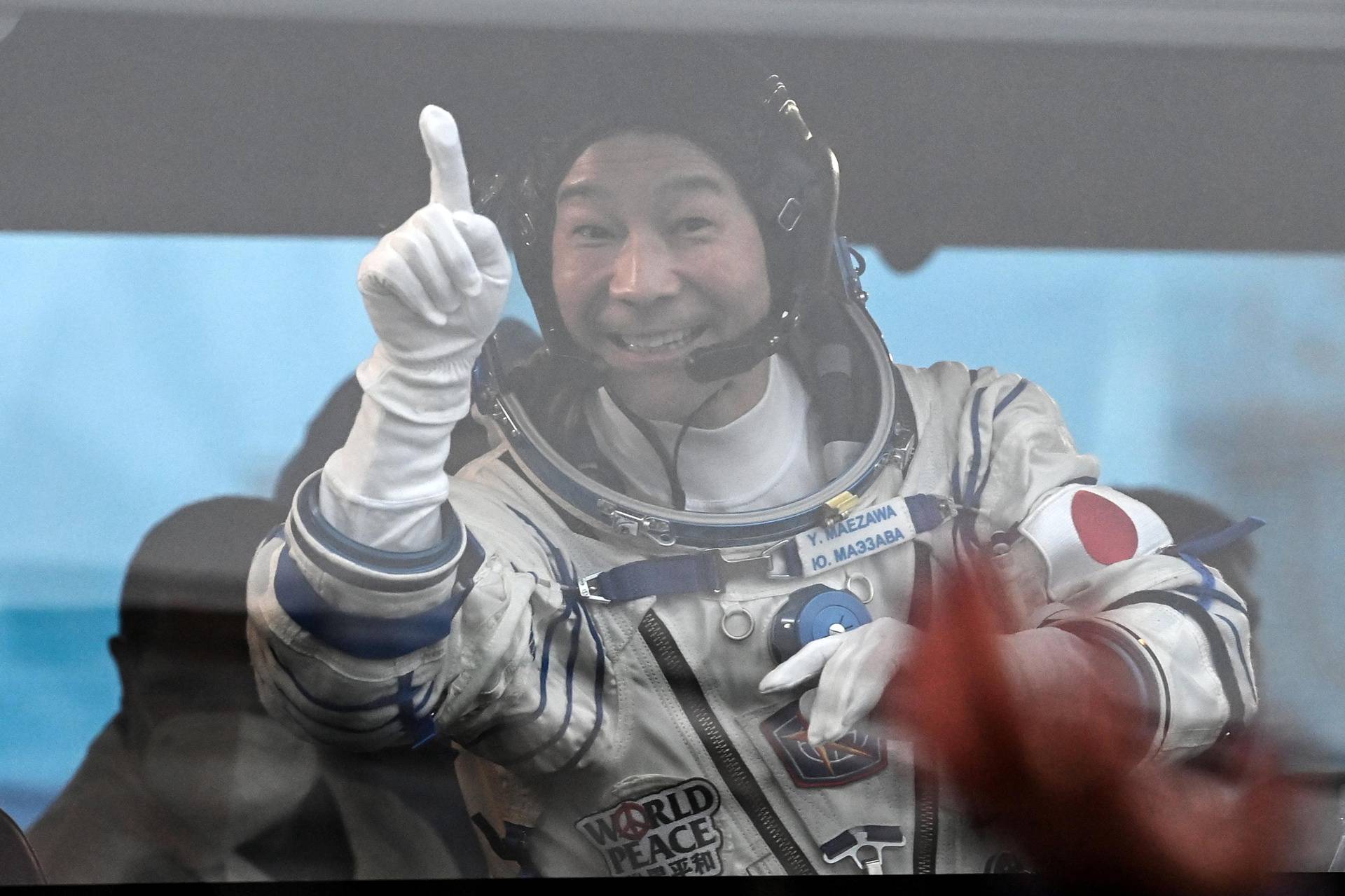 Japanese entrepreneur Yusaku Maezawa waves from a bus as he departs for his launch to the International Space Station (ISS) at the Baikonur Cosmodrome