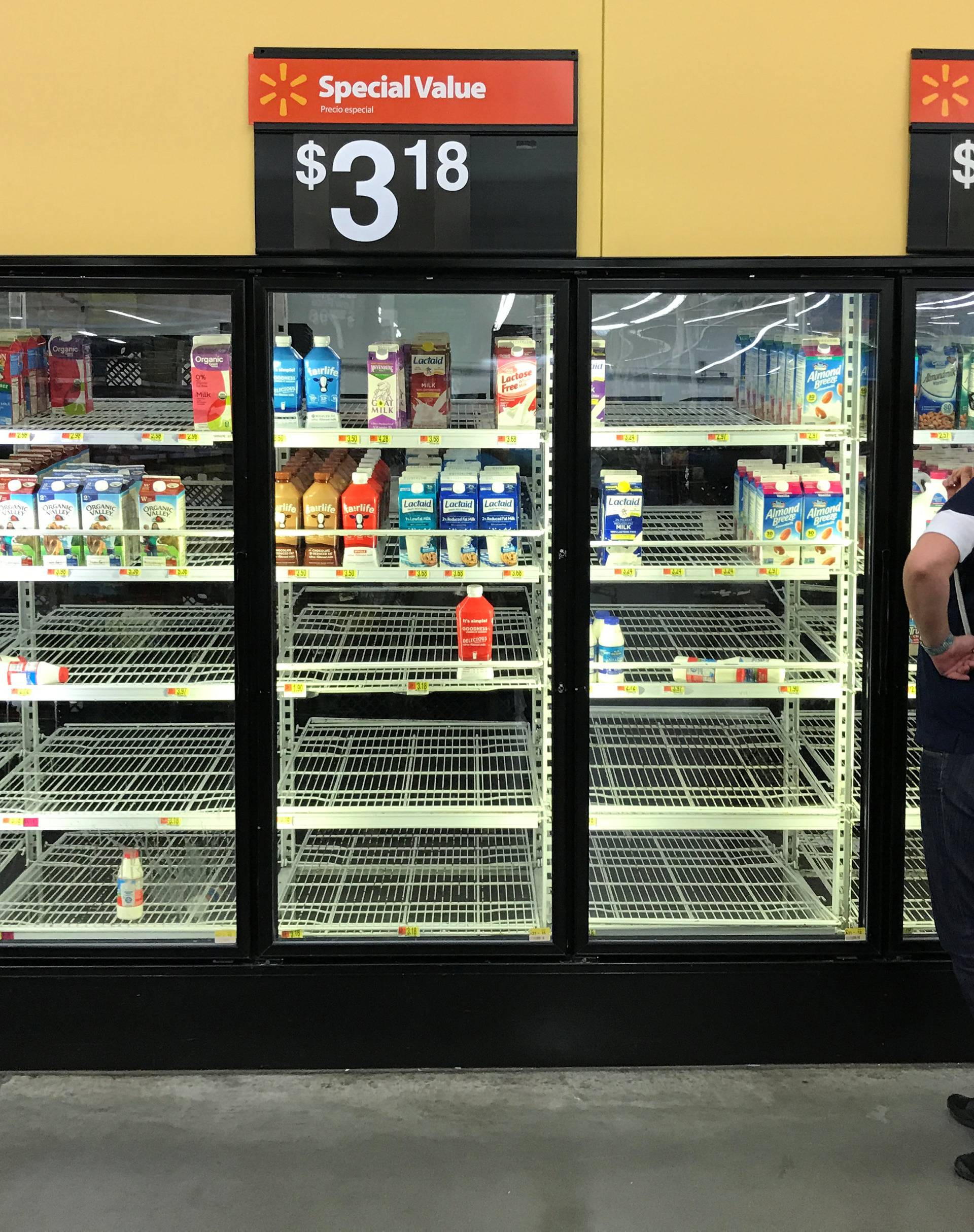 A unidentified woman looks over bare refrigerator shelves in a Walmart store in Houston