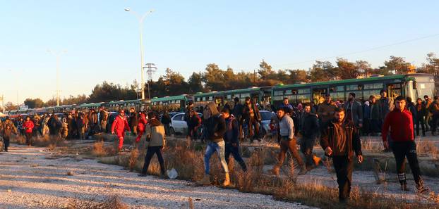 Evacuees from rebel-held east Aleppo, disembark from buses upon their arrival to the town of al-Rashideen