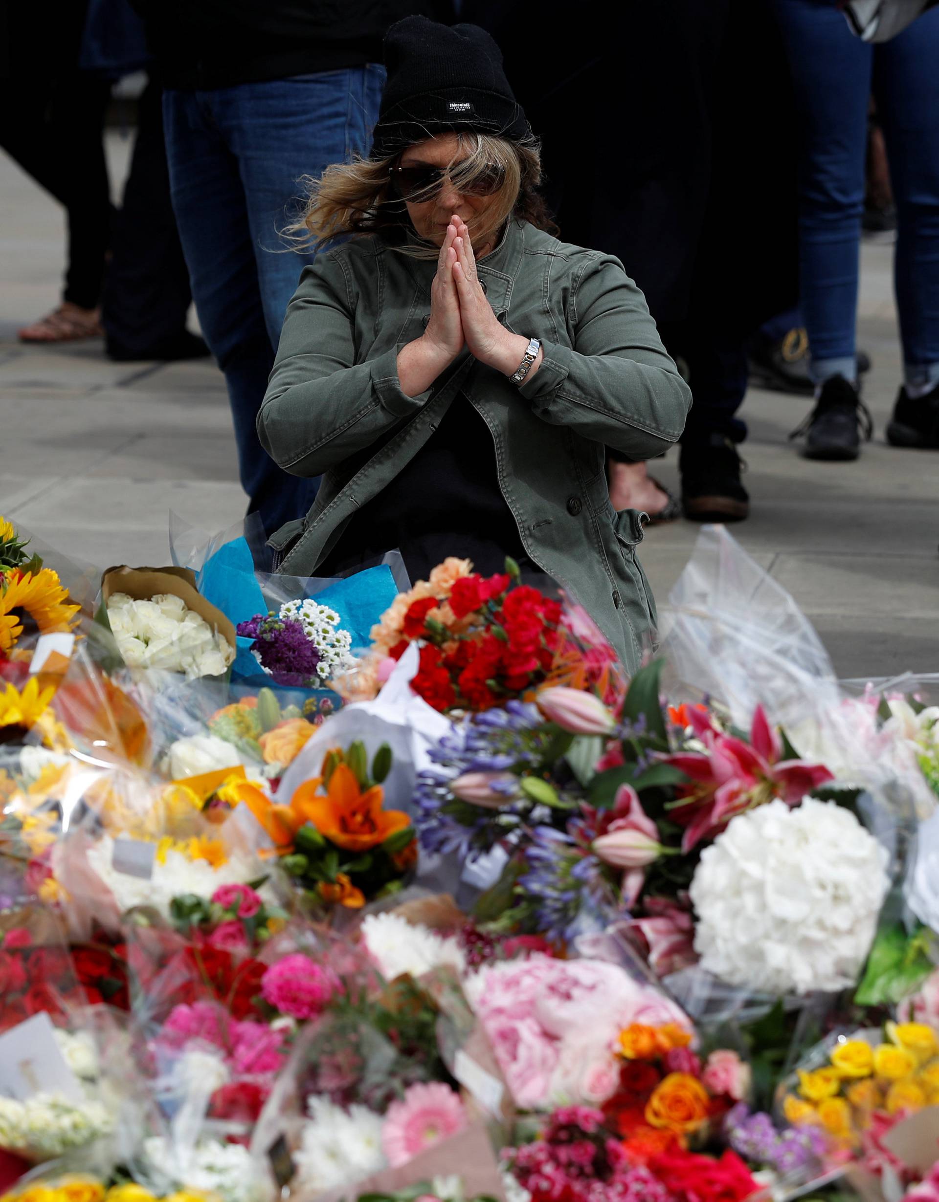 A woman sits in front of floral tributes on the south side of London Bridge near Borough Market after an attack left 7 people dead and dozens of injured in London