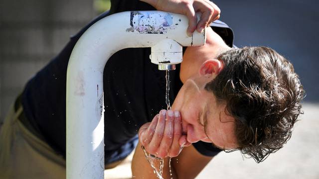 FILE PHOTO: A man drinks water from a public drinking establishment during a heatwave in Nijmegen