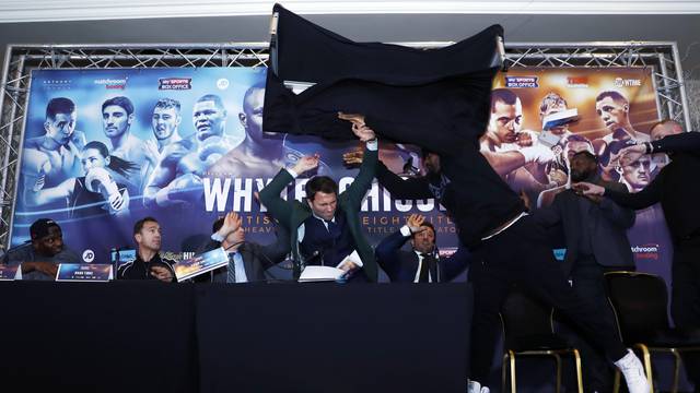 Dillian Whyte, trainer Mark Tibbs, Sky Sports' Adam Smith, promoter Eddie Hearn and promoter Kalle Sauerland look on as Dereck Chisora throws a table during the press conference