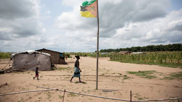 A woman walks past a Mozambique flag in Ndedja resettlement camp in Nhamatanda District, Mozambique