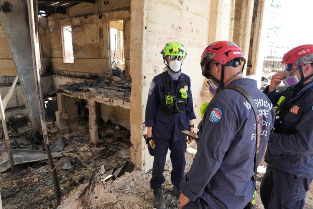 Members of FEMA Urban Search and Rescue teams comb through destroyed Lahaina neighborhoods