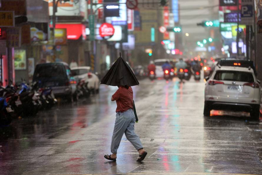 Person braves strong winds while crossing a street in Taipei