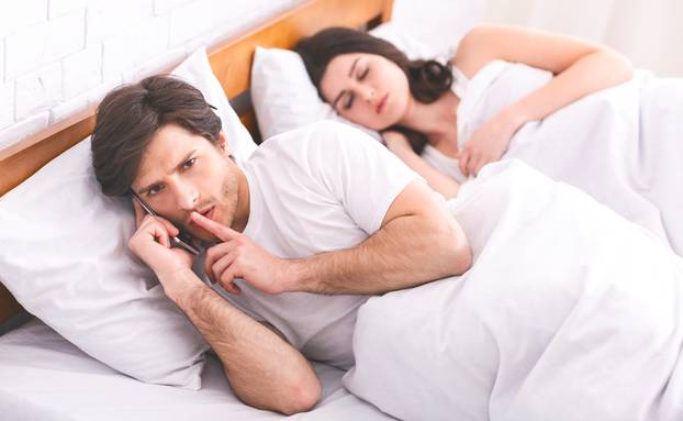 Man cheater talking privately on cellphone in family bed