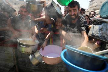 Palestinians wait to receive food from a charity kitchen, in Gaza City