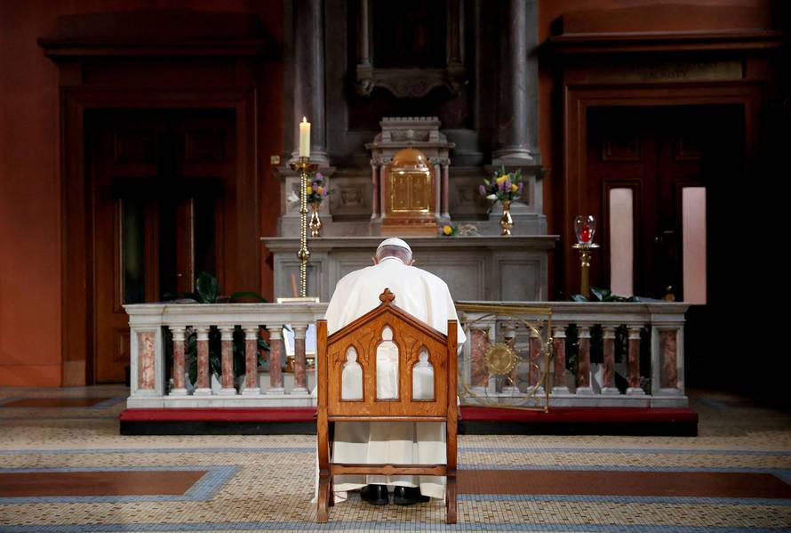 FILE PHOTO: Pope Francis prays in front of a candle lit to remember victims of abuse by the church, inside St Mary's Pro Cathedral during his visit to Dublin