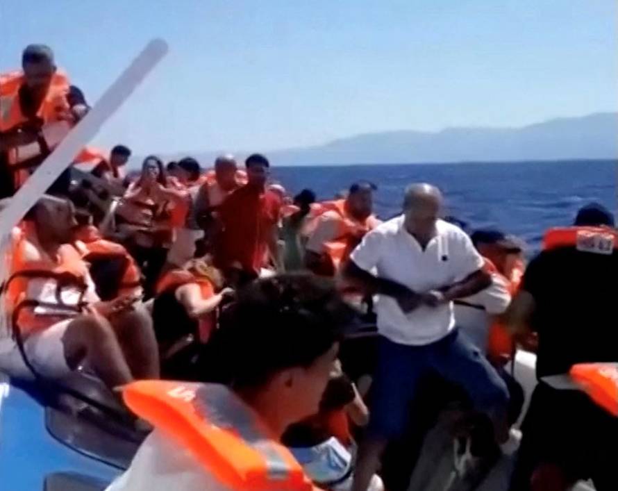 Passengers wait to be rescued on the top of a capsized vessel off the coast of Northern Cyprus