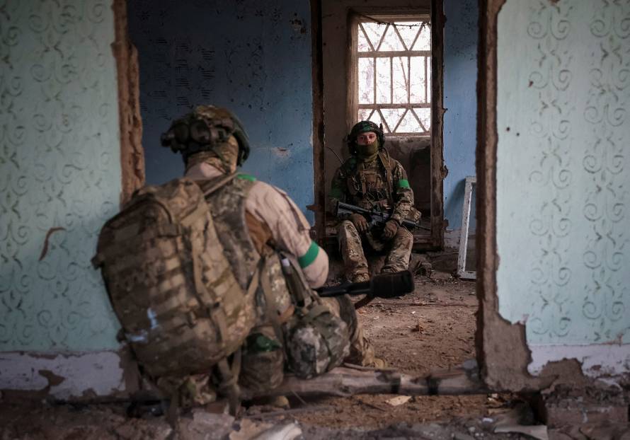Ukrainian servicemen hide from a Russian combat drone in a building damaged by Russian military strike in the frontline town of Kostiantynivka