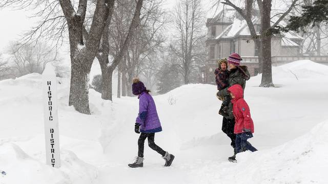 The Motz family walks through blowing snow as weather conditions worsen