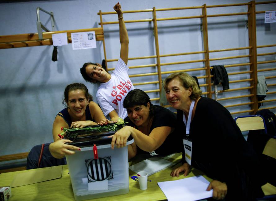 Poll workers celebrate after polls closed at a polling station for the banned independence referendum in Barcelona