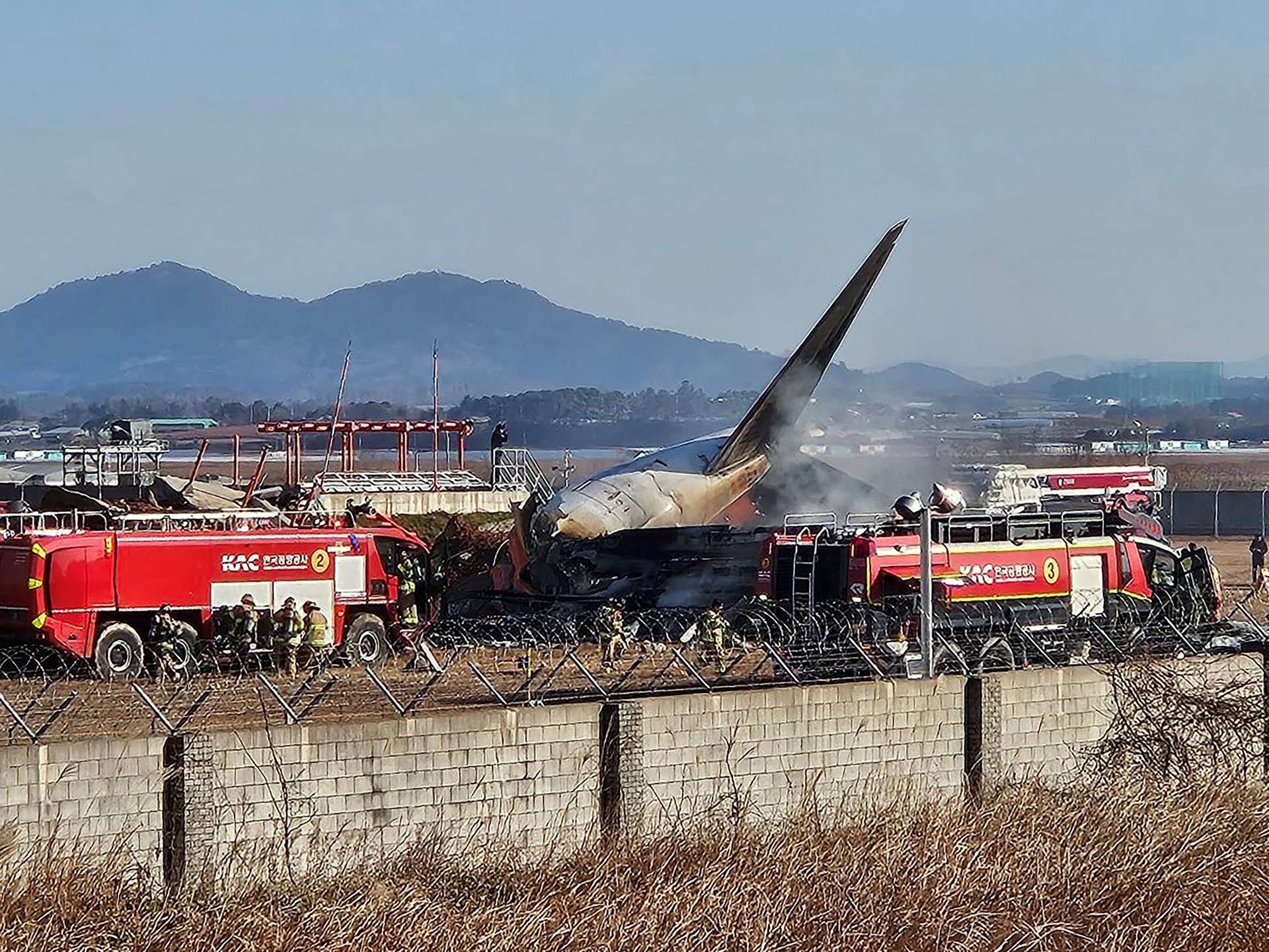 Firefighters carry out extinguishing operations on an aircraft which drove off runaway at Muan International Airport in Muan