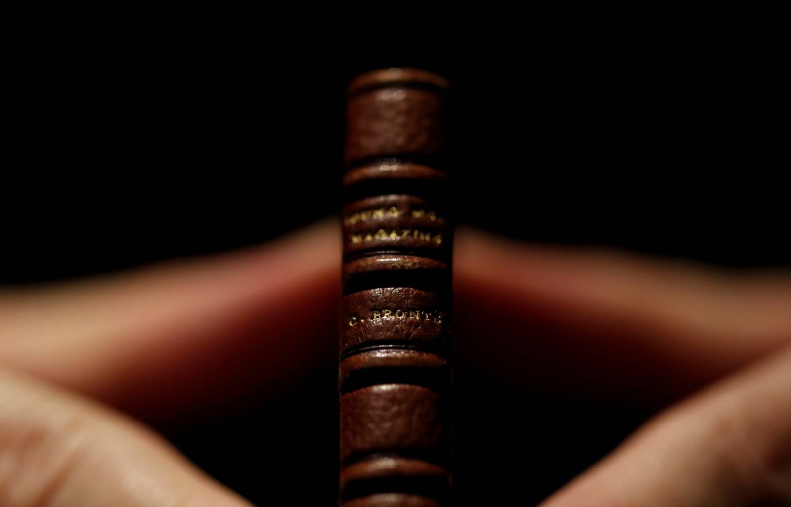 An employee displays the second issue of Young Men's Magazine, a miniature manuscript dated 1830, written by Charlotte Bronte when she was 14 years old, before being put on auction at Drouot auction house in Paris