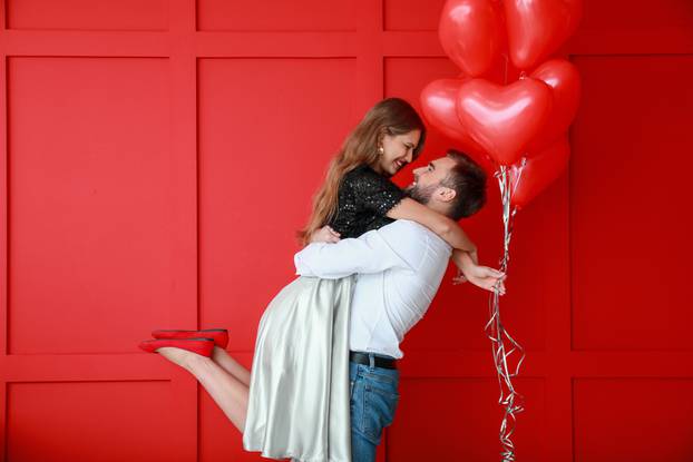 Happy,Young,Couple,With,Heart-shaped,Balloons,On,Color,Background.,Valentine's