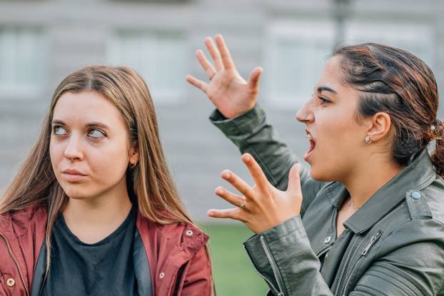 two female friends arguing in the street outdoors