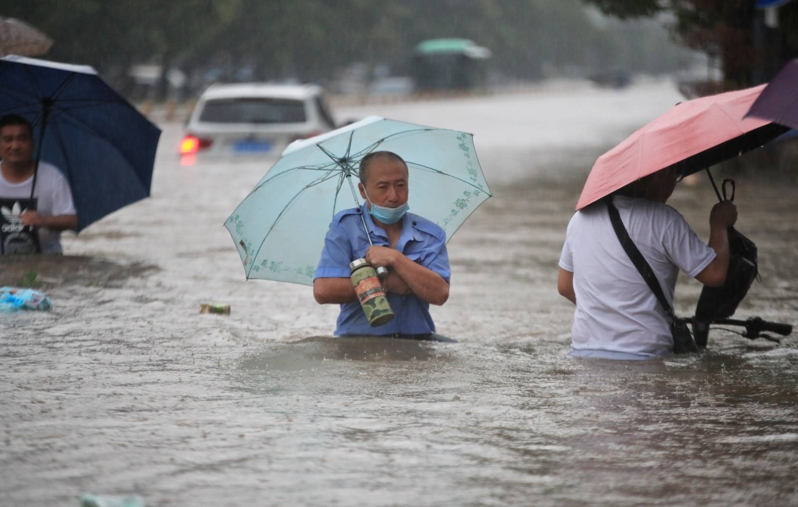 Residents wade through floodwaters on a flooded road amid heavy rainfall in Zhengzhou