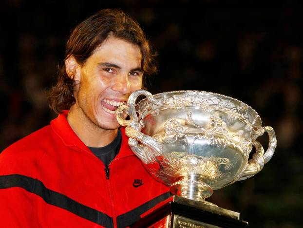 FILE PHOTO: Spain's Nadal bites the trophy as he poses after winning his men's singles final match against Switzerland's Federer at the Australian Open