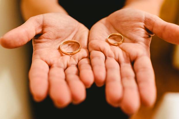 Newlywed rings shown in the hands of the bride and groom.