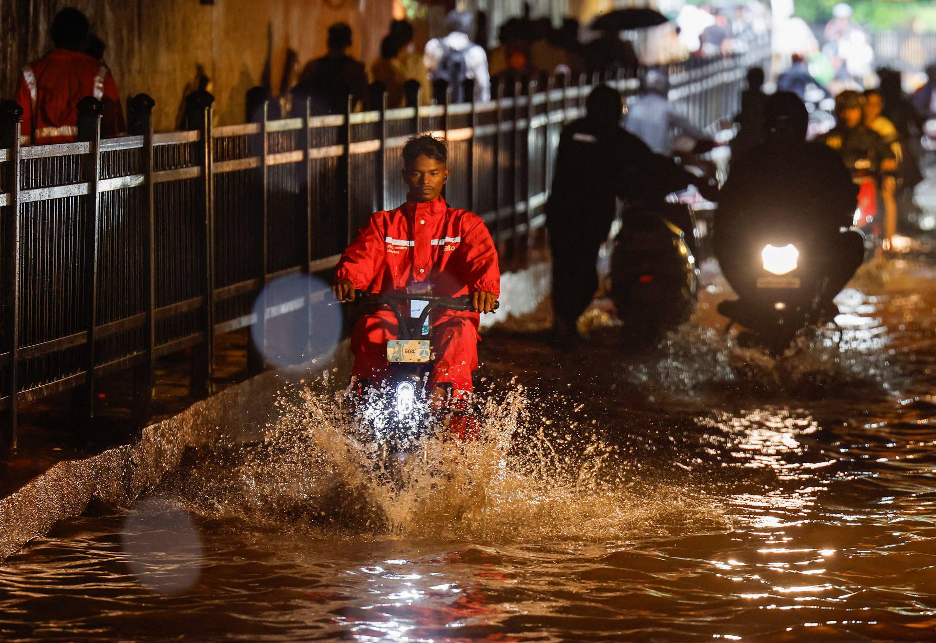 A delivery person rides an electric scooter in a waterlogged subway after heavy rains in Mumbai