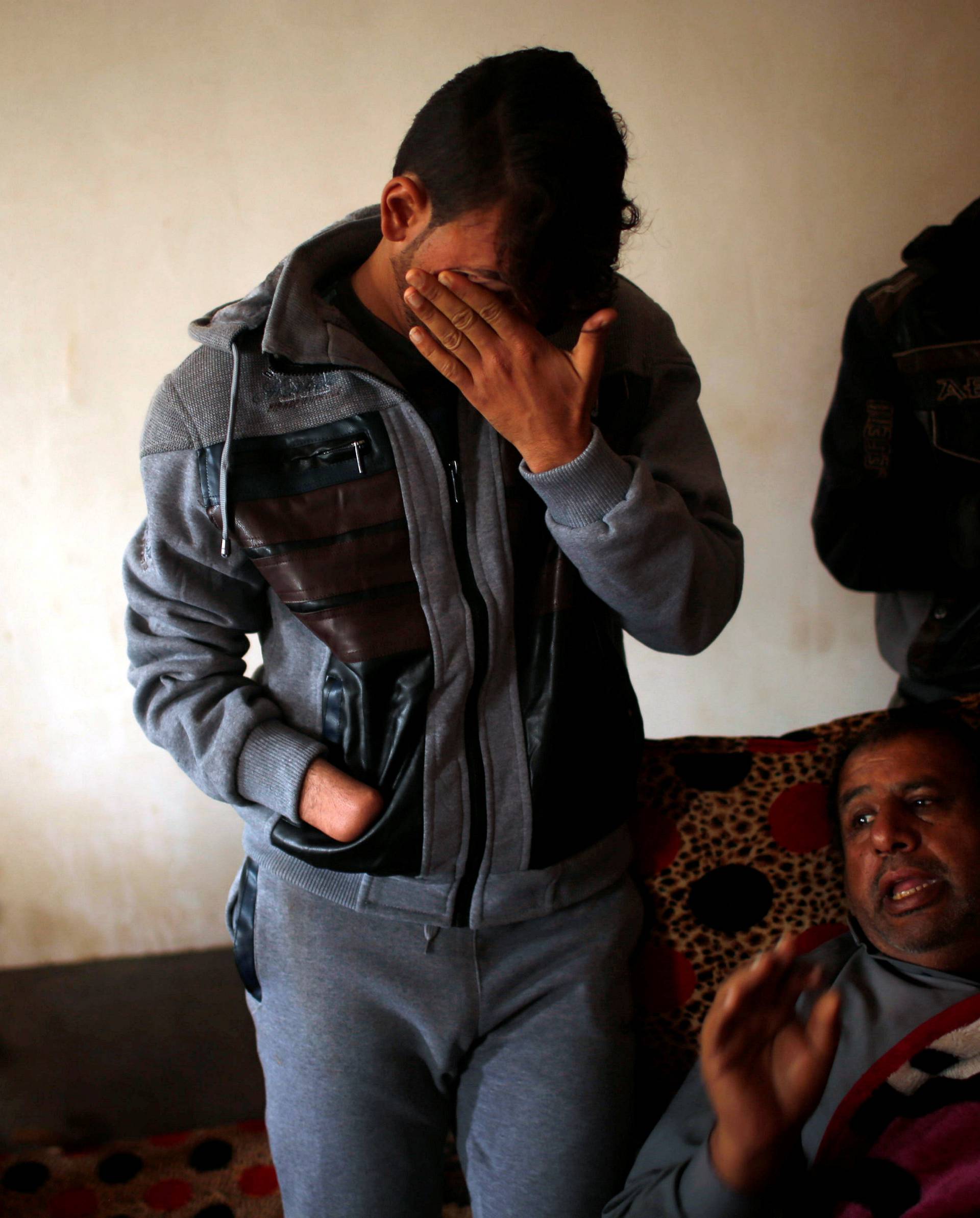 Azad Hassan, whose hand was chopped off by Islamic State militants, cries as he stands beside his wounded father in a house at Nimrud village, south of Mosul