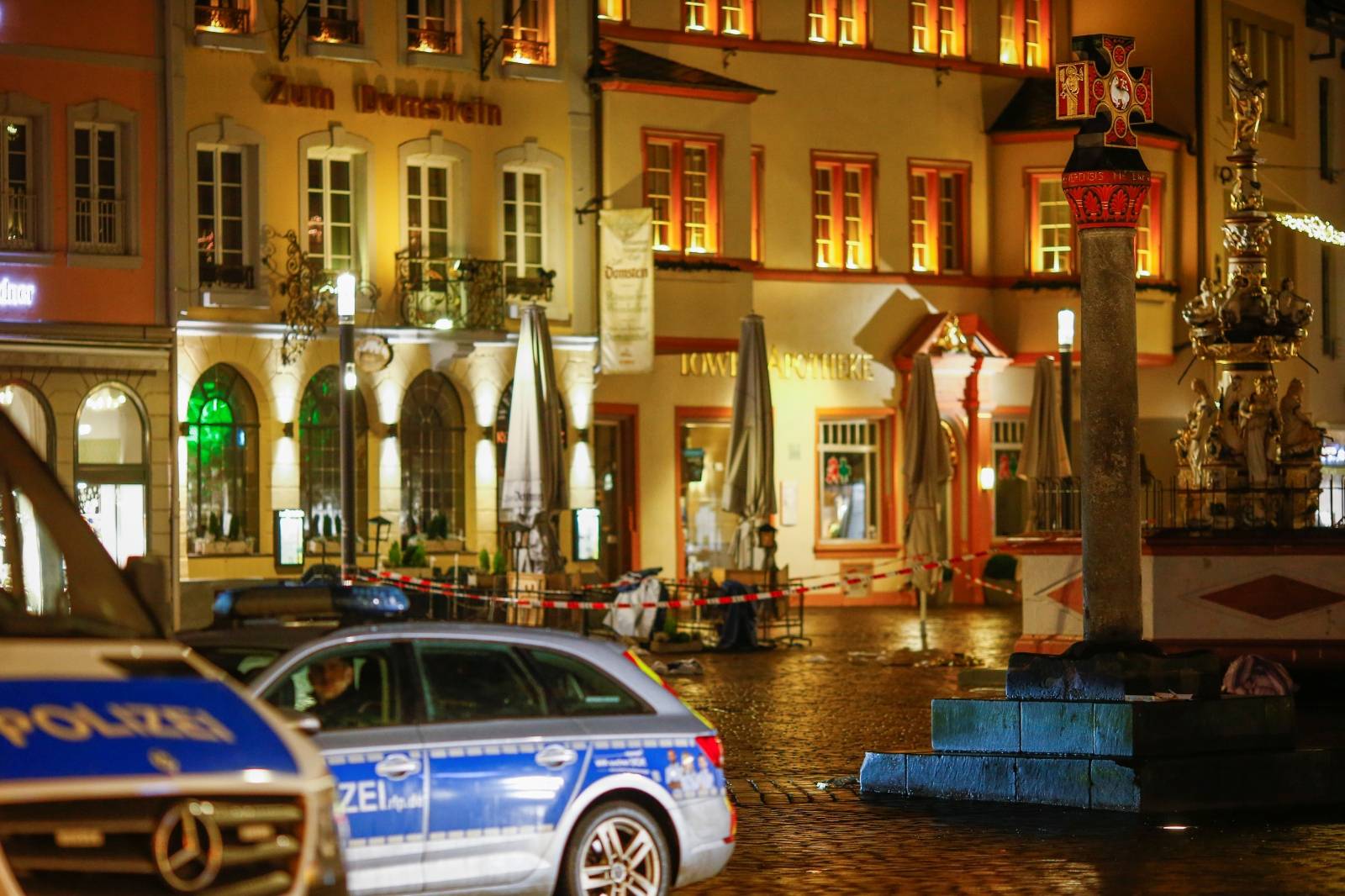 Police vehicles are parked next to the site where a car crashed into pedestrians in Trier