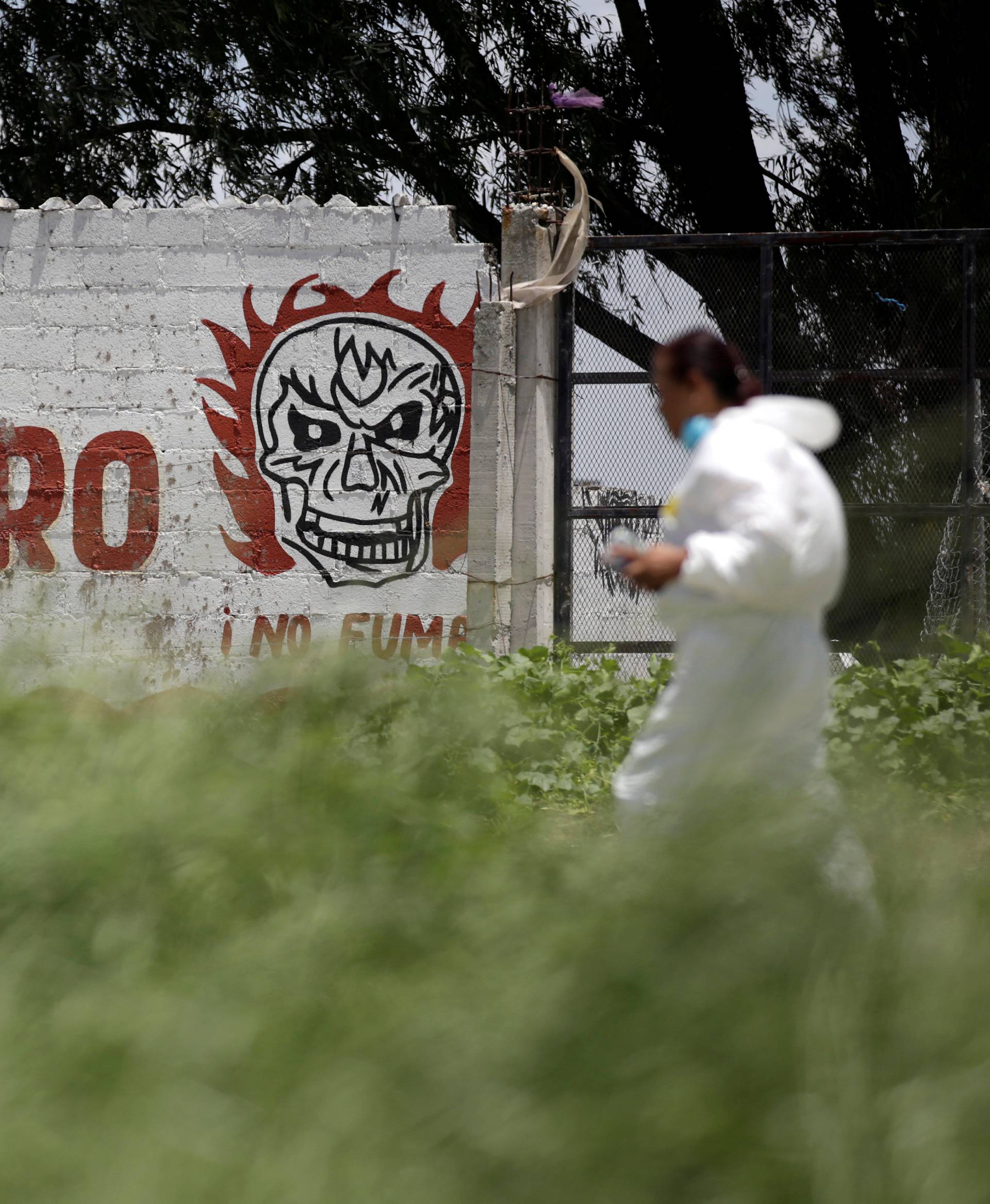 A forensic technician walks by a wall reading "Danger" while inspecting a site damaged due to fireworks explosions in the municipality of Tultepec