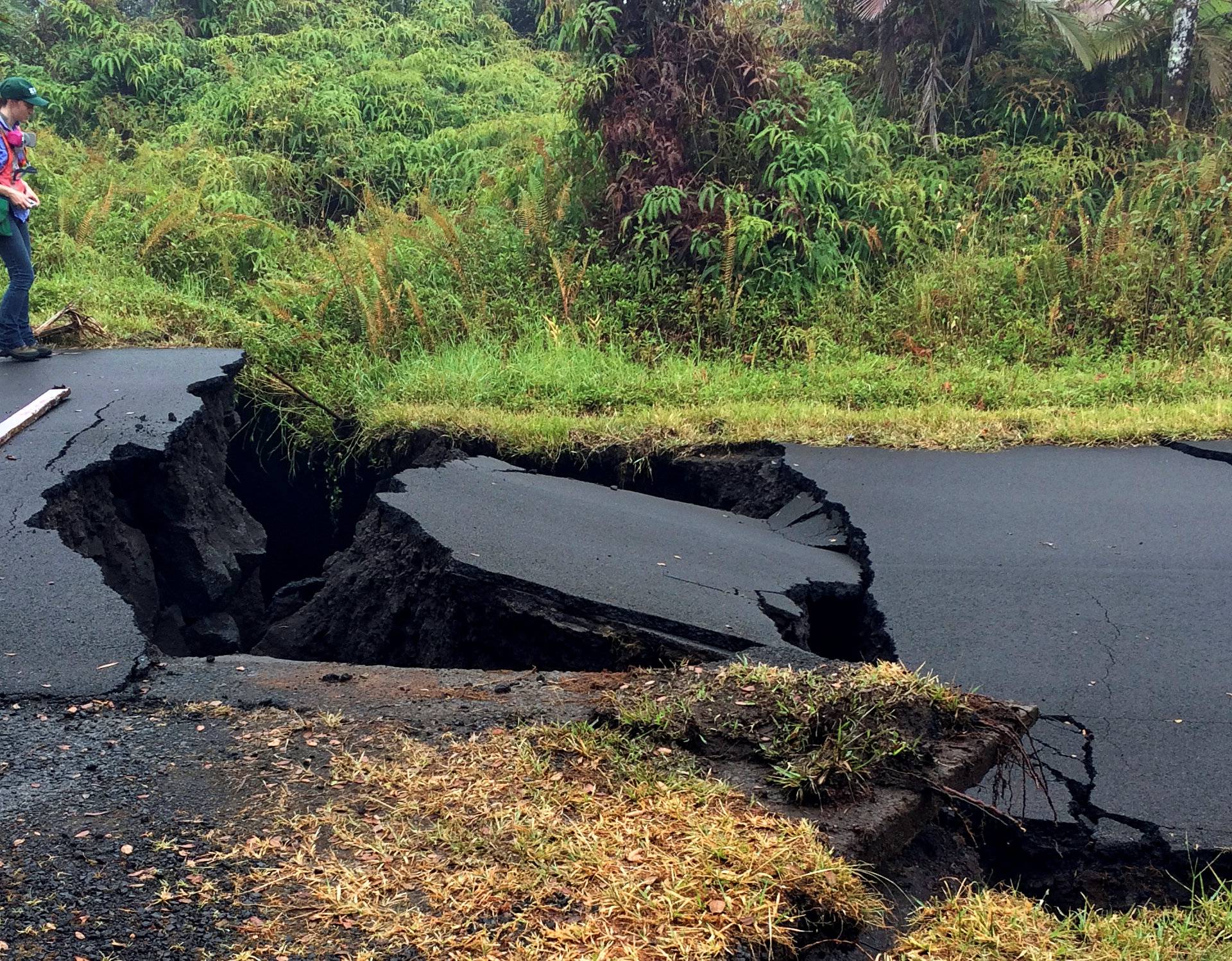 A geologist inspects cracks on a road in Leilani Estates, following eruption of Kilauea volcano, Hawaii