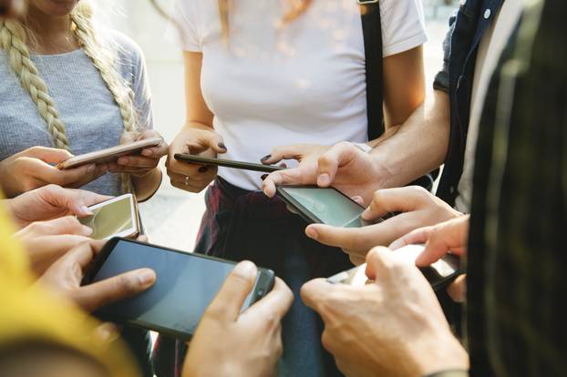 Young adult friends using smartphones together outdoors youth cu