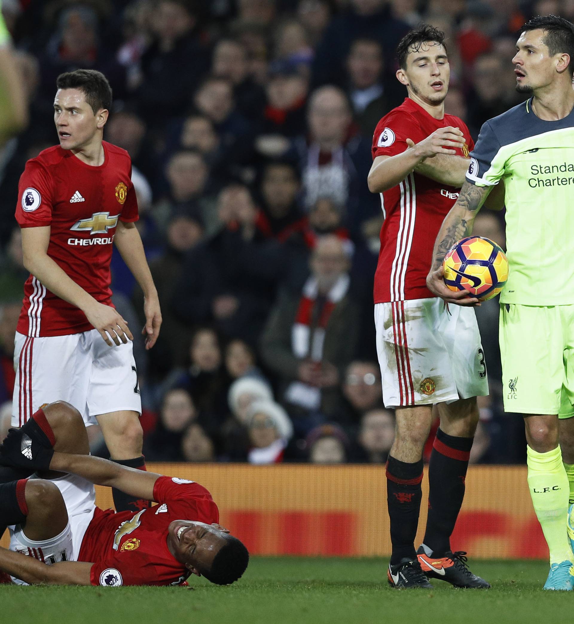 Manchester United's Anthony Martial lies injured after a foul by Liverpool's Dejan Lovren