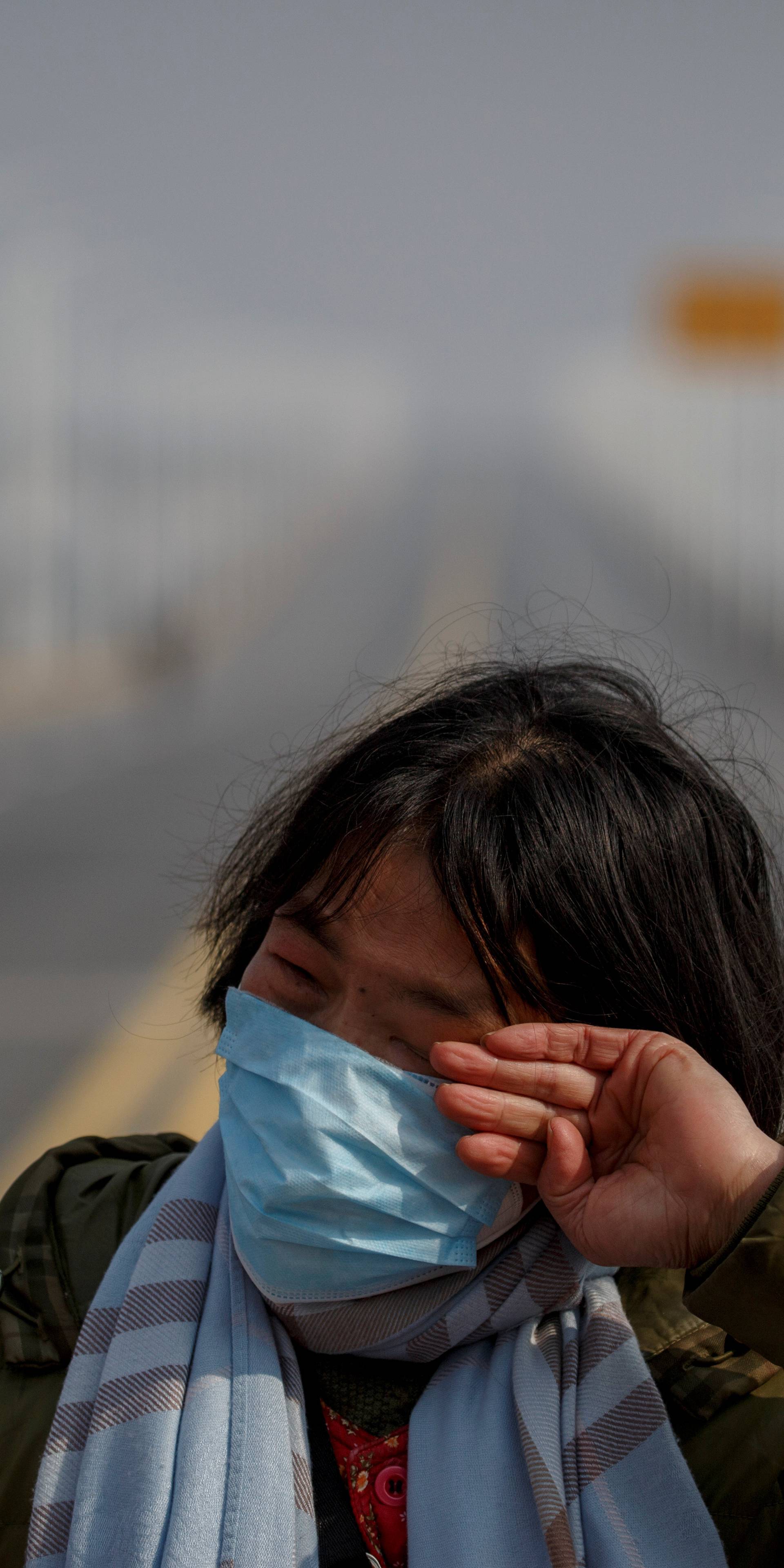 A mother reacts as she pleads with police to allow her daughter to pass a checkpoint for cancer treatment after she arrived from Hubei province at the Jiujiang Yangtze River Bridge in Jiujiang